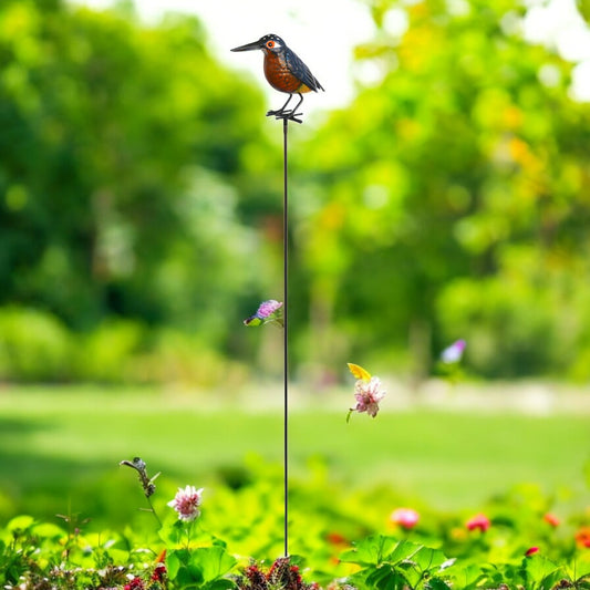 a bird sitting on top of a pole in a garden